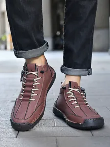 Detailed view of hand-stitched seams on brown leather men's mid-top casual boots