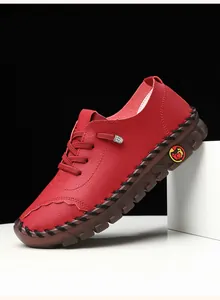 Detailed side view of red handmade leather shoes with coarse black stitching and soft soles