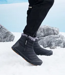Detail of black winter snow boot with side zipper and faux fur lining in a snowy setting