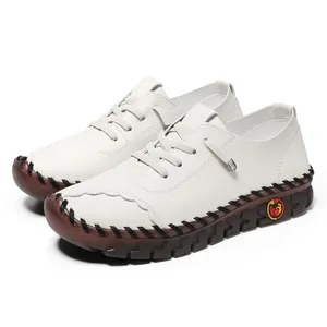 Detail of white leather casual flats with brown rubber sole and visible hand stitching