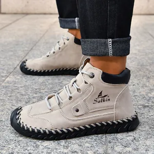 Detailed view of beige suede leather boots with black stitching and rubber soles