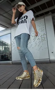 Dettaglio di sneaker alte con paillettes dorate e spessa suola in gomma bianca