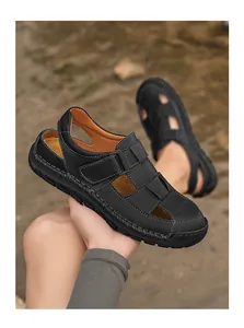 Detail of men's black leather sandals with white stitching and velcro strap