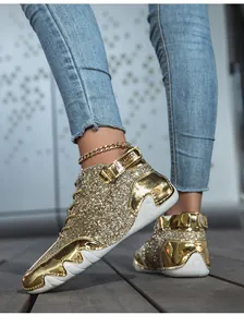 Vista delle scarpe alte dorate con paillettes, inserti in pelle e catena alla caviglia