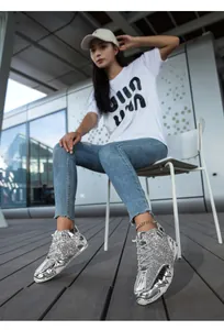 Dettaglio di sneaker alte con paillettes argento con onde metalliche e suola bianca