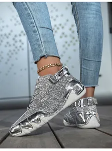 Dettaglio delle sneakers con paillettes argento con inserti metallici e catena alla caviglia