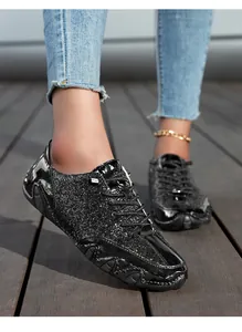 Details von glitzernden schwarzen Freizeitschuhen mit Lacklederbesatz und Wellensohle