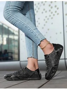 Nahaufnahme schwarzer Pailletten-Freizeitschuhe mit Lacklederbesatz auf Blue Jeans
