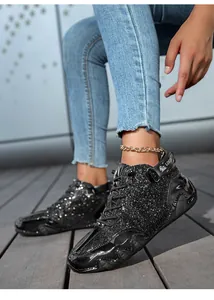 Dettaglio di stivaletti neri con paillettes e nastro con logo LDEQ sul tallone