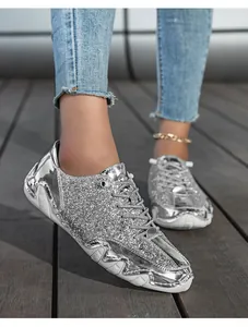 Detail der glitzernden silbernen Pailletten auf modischen Low-Top-Sneakern mit Schnürsenkeln