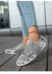 Nahaufnahme von silbernen Pailletten-Sneakern mit metallischen Spiegeldetails und dicken Sohlen