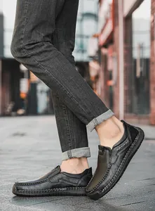 Detail of handcrafted stitching on men's black leather loafers in a casual street setting
