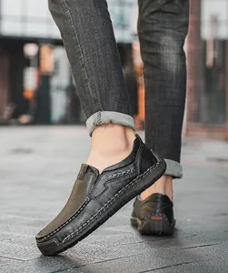 Outdoor shot of men's black leather slip-on loafers featuring heavy stitching and rubber soles