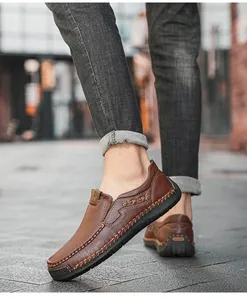 Macro detail of brown leather loafers with white stitching and textured pebble finish