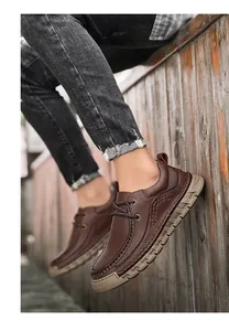Dettaglio di scarpa in pelle marrone scuro da uomo con cuciture a mano e suola spessa