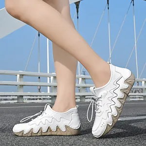 Outdoor shot of white sneakers with brown wavy platform soles and lace-up toggle on pavement