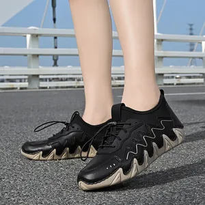 Detail of black outdoor shoes with silver wave accents and serrated thick soles on asphalt