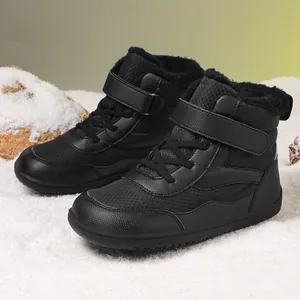 Children's black thermal high-top snow boots with non-slip soles on a snowy background