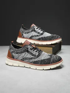 Detail of breathable fly-knit mesh material and brown leather accents on men's shoe