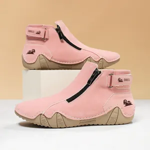 Detalle de botines de gamuza rosa con cremalleras laterales y suelas con textura ondulada