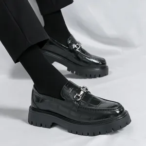 Dettaglio di mocassini neri con trama a coccodrillo e fibbia in metallo argento lucido