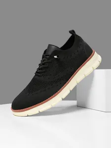 Detail view of black knit mesh sneaker with white chunky sole and brown welt line