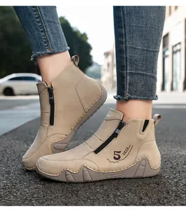 Detail of handmade stitching and side zipper on beige retro autumn flat ankle boots