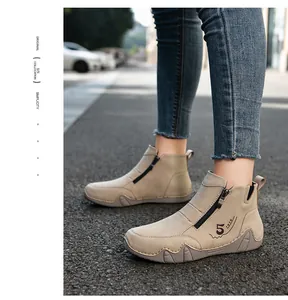 Detail view of beige faux suede boots with side zipper and durable rubber sole on asphalt
