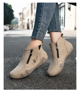 Close-up of beige suede ankle boots featuring side zipper and vintage number print detail