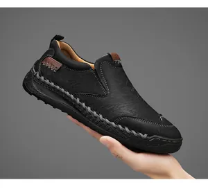 Vue détaillée de mocassins en cuir noir pour hommes cousus main tenus en main