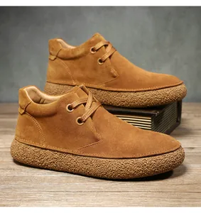 Detailed close-up of brown suede desert boots with textured thick rubber soles on wood