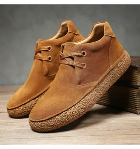 Close-up of brown suede desert boots with textured rubber soles and round laces
