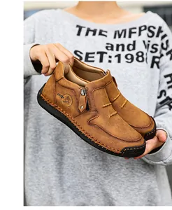 Détail de bottines en daim marron avec fermeture éclair latérale et coutures faites main