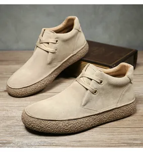 Detail shot of light brown suede mid-top boots featuring textured thick soles on wood