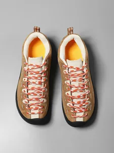 Λεπτομέρεια από καφέ καστόρινια sneakers με πορτοκαλί κορδόνια και μύτη από καουτσούκ