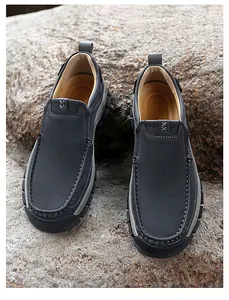 Detail of grey slip-on leather shoes with white contrast stitching on natural rocks
