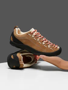 Λεπτομέρεια από καφέ σουέτ sneakers με κόκκινα-λευκά υφαντά κορδόνια και ενισχυμένο δάχτυλο