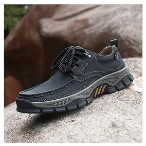 Close-up of black leather outdoor shoes with rugged rubber sole on natural rock background