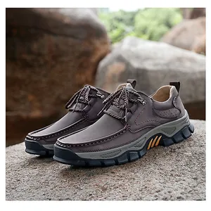 Detailed view of brown leather outdoor shoes with rubber non-slip soles on rocks