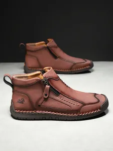 Detail von dunkelbraunem Lederstiefel mit Reißverschluss, Handnaht und Logo-Prägung