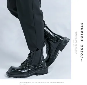Detail of black crocodile-embossed leather boots with thick rubber soles and laces