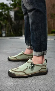 Detail van handgemaakte lichtgroene leren loafer met dikke stiksels en een rubberen zool
