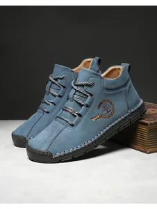 Detailed view of blue nubuck leather boots with hand-stitched rubber soles and logos