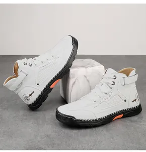 Detail van witte leren hoge veterschoen met stiksels en oranje accenten op de zool