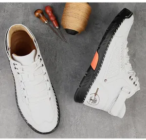 Bovenaanzicht van witte leren hoge sneakers met oranje accenten op donkere achtergrond