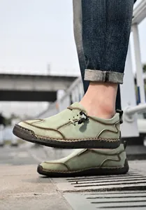 Detail van lichtgroene lederen loafers met handgemaakte stiksels en rubberen zolen