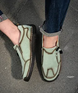 Detail van lichtgroene leren loafers met handgemaakte stiksels en zwarte rubberen zool