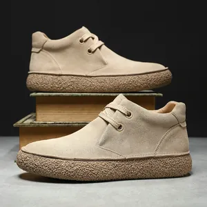 Vintage men's beige suede desert boots with textured thick rubber sole on retro books