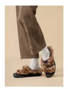 Dettaglio di scarpe in pelliccia sintetica marrone con chiusura a coulisse e calze