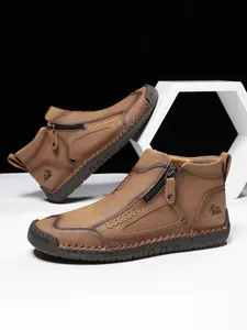Detail brauner Lederstiefel mit Handnaht, seitlichem Reißverschluss und Gummisohle mit Profil